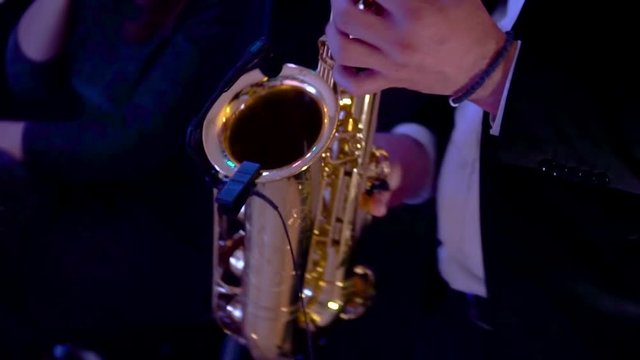 A saxophonist wearing suit performing an amazing solo. Saxophonist musician playing saxophone at the concert or party