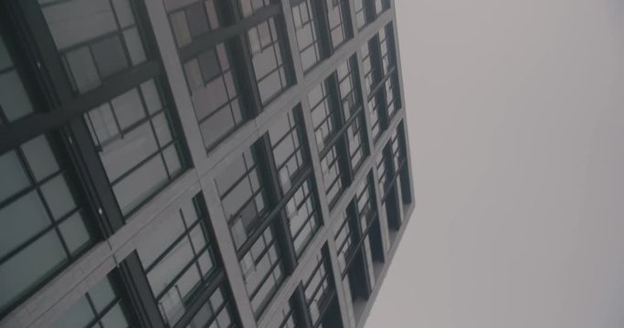 Montreal, Canada - April 15 : Worm eye arc shot of urban modern building facade against cloudy sky, filmed while driving on de la Commune street.