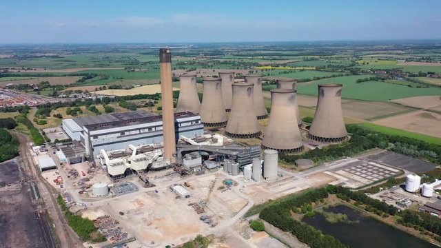 Aerial footage of the Eggborough Power station showing the eight cooling towers and chimneys along side farmers fields on a bright sunny summers day located in Goole, West Riding of West Yorkshire