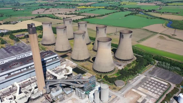 Aerial footage of the Eggborough Power station showing the eight cooling towers and chimneys along side farmers fields on a bright sunny summers day located in Goole, West Riding of West Yorkshire