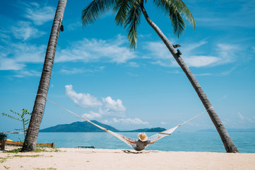 Young woman lying in a hammock on beach