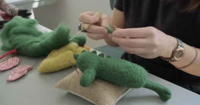 Woman making wool art doll toy at table close up. Female sitting and creating ooak doll at home. Needle Felted Handmade and creative skills