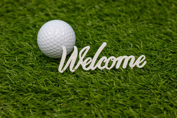 Golf ball is on green grass with word welcome golfer