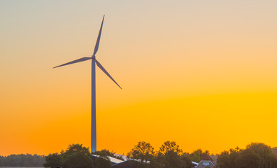 Obraz premium Wind turbine in a yellow sky in sunlight at sunrise in an early spring morning