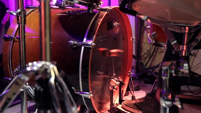 A drummer is drumming in the Studio. Plays the kick drum pedal. The musician behind the drum kit. Static video recording.