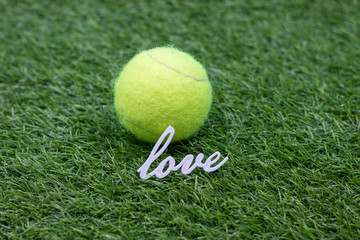 Tennis ball with word Love on green grass