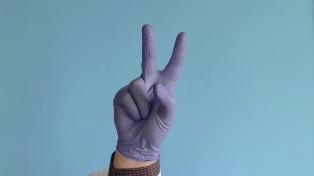 hand of doctor in a white coat and gloves isolated against the blue background and counting from 0 to 5. concept of the final countdown