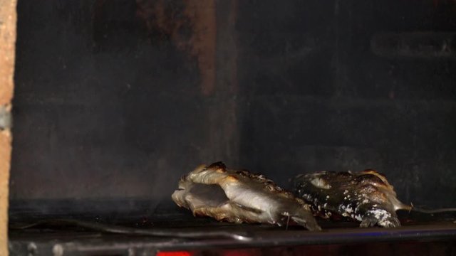 cook taking grilled meat from grill to dish