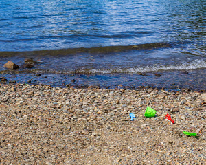 color plastic toys on the shore at the beach lake british columbia canada sunny summer day.