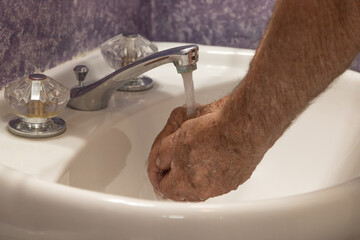 Bathroom sink cupping hands under running water