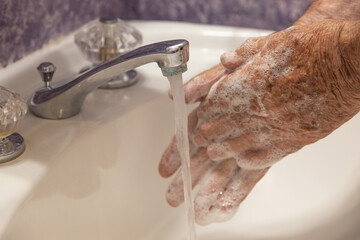 man washing hands in bathroom with soap