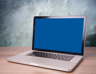 Fototapeta premium Laptop or notebook with blank screen on wood table in blurry background