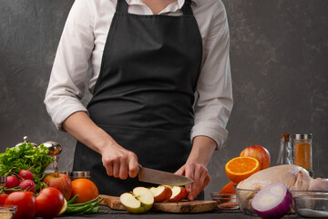 The chef cuts fresh apples for baking chicken, turkey, or duck for a festive dinner. Recipe book, restaurant business, cooking. Cooking and gastronomy