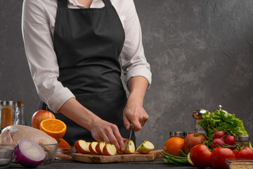 The chef cuts fresh apples for baking chicken, turkey, or duck for a festive dinner. Recipe book, restaurant business, cooking. Cooking and gastronomy