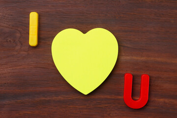 Letters I and U with a blank symbolic heart shaped sticker. Short Message I love you