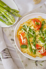 Omelet with asparagus with cheese and tomatoes.  Omelet with asparagus on a white plate.