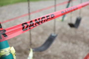 Danger tape is wrapped around playground equipment, indicating the park is closed due to Covid-19 concerns.