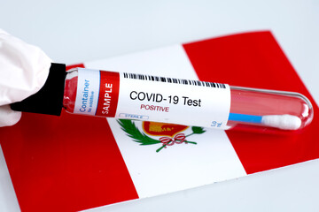 Testing for presence of coronavirus in Peru. Tube containing a blood sample that has tested positive for COVID-19. Peruvian flag in the background.