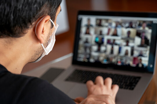 Man using a mask and having a video conference with work team amid COVID-19 pandemic.