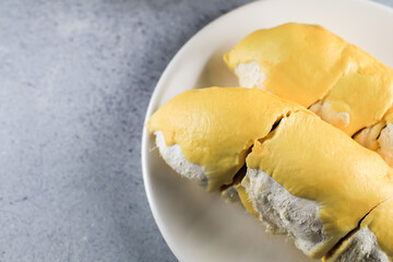 Close up durian the king of fruit in Thailand on white plate.Summer tropical Thai traditional fruits so delicious,spiky peel,sweet and good smell. Ripe durian has been peel yellow gold color.