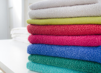 Obraz na płótnie Canvas Stack of colorful and soft towels on white table.