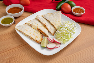 Mexican cheesy quesadilla made with Monterey jack cheese and marinated chicken. Made by melting cheese inside of a large flour tortilla.