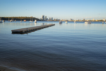 Fototapeta na wymiar A calm morning at Matilda Bay Reserve, Perth. The city can be seen in the background with boats in the bay. 