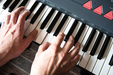 Male playing the piano keyboard. Top view hands close up