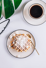 Flat lay of Belgian waffles with marshmallows and coffee on white background. Top view. Minimal concept