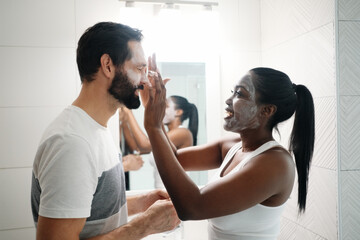 Woman Applying Beauty Mask And Skin Cleanser To Man