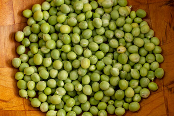 Closed up to a fresh green peas into a wooden brown bowl