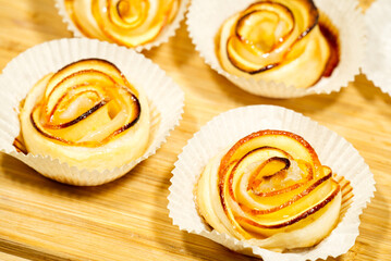 Buns of dough with apple slices, similar to roses on the kitchen board, homemade dessert