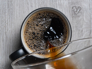 black coffee being poured into mug sitting on white table with heart engraved into it