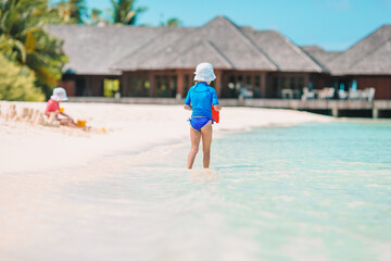 Two kids making sand castle and having fun at tropical beach
