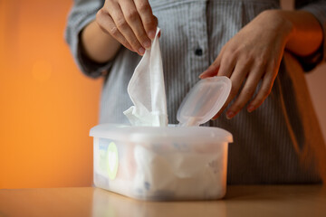 Wet wipes are universal an practical: woman take one wipe from big plastic box package for cleaning