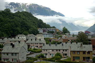 Fototapeta na wymiar Cityscape of Tyssedal village near Odda,Norway,houses with old norwegian traditional roof,scandinavian nature,morning beauty,gloomy day with low clouds,print for wallpaper,poster,cover design,calendar