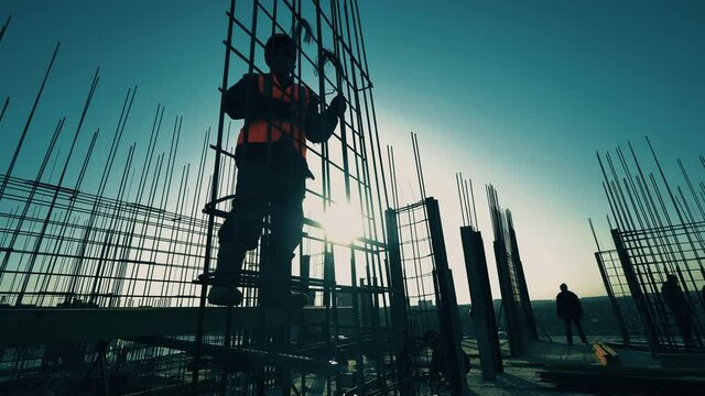 Contractor, construction worker fixes reinforcement on building.