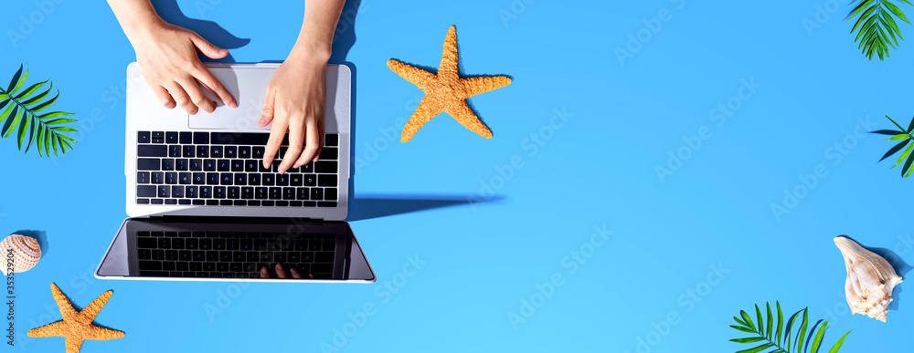 Poster person using a laptop computer with summer theme objects - flat lay