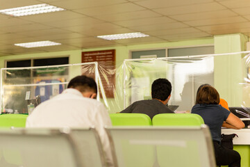 Obraz premium Social distancing customer at counter service with staff behind Plastic partition counter coronavirus protection. new normal.