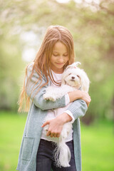 Little smiling girl playing and hugging puppy in the park