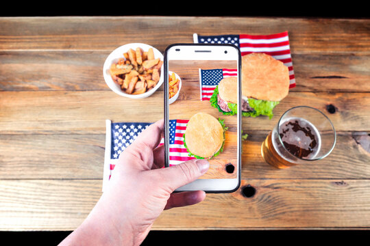 food concept, technology, united states, 4th of july, independence day Women's hands with cell phones taking pictures of food. Photo on mobile phone screen.