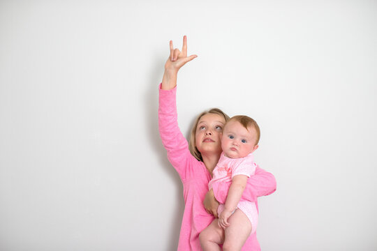 Young Girls With Face Masks On A White Background With Room For Text Or Whitespace. Sisters Acting Silly. Kids With Facemasks. 