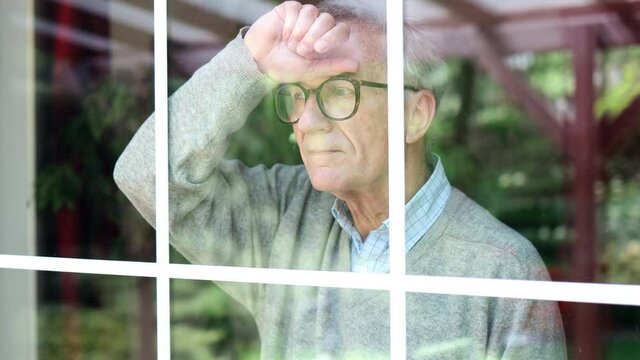 Senior man looking out of window at home
