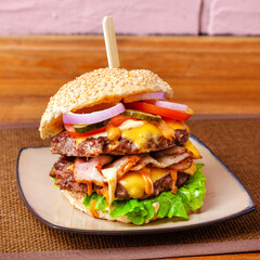 Burger, Meat, cheese and fresh vegetables sandwich, closed, on wooden background