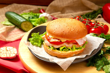 Burger, Meat, cheese and fresh vegetables sandwich, closed, on wooden background