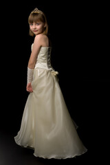 A little girl in a long, elegant dress of a princess on a black background.