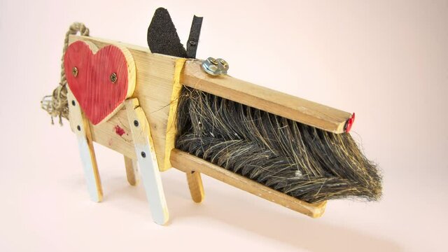 A closeup of an isolated dog on a light changing background. A dog is made of wooden upcycled elements like an old broom. Zero waste creative concept.