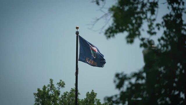 Static shot of Kansas state flag blowing in the wind on a clear blue sky day