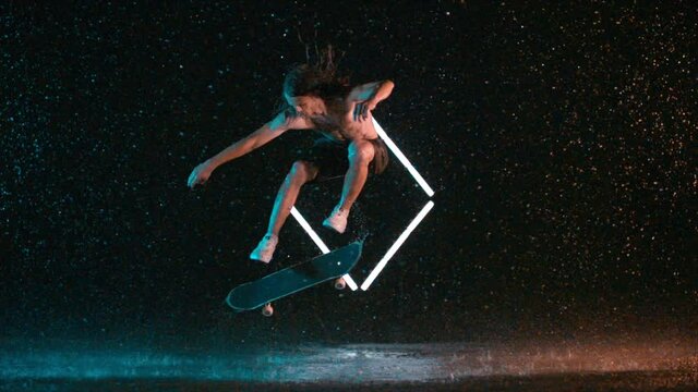 Amazing skilled skateboard hardflip trick in wet rain studio effect, caucasian man