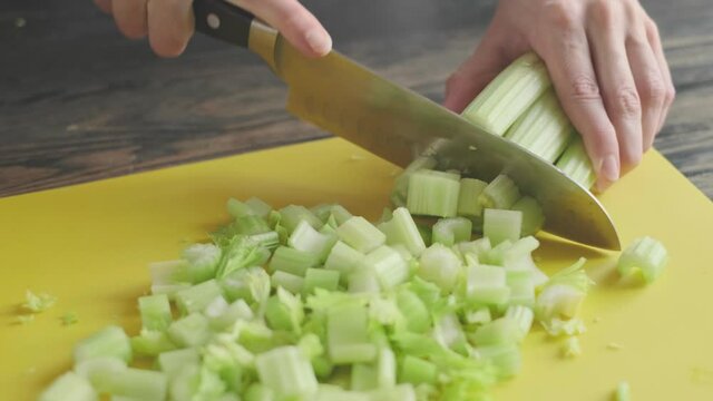 a woman prepares slices on a cutting board ingredients for a celery smoothie and puts them in a blender bowl